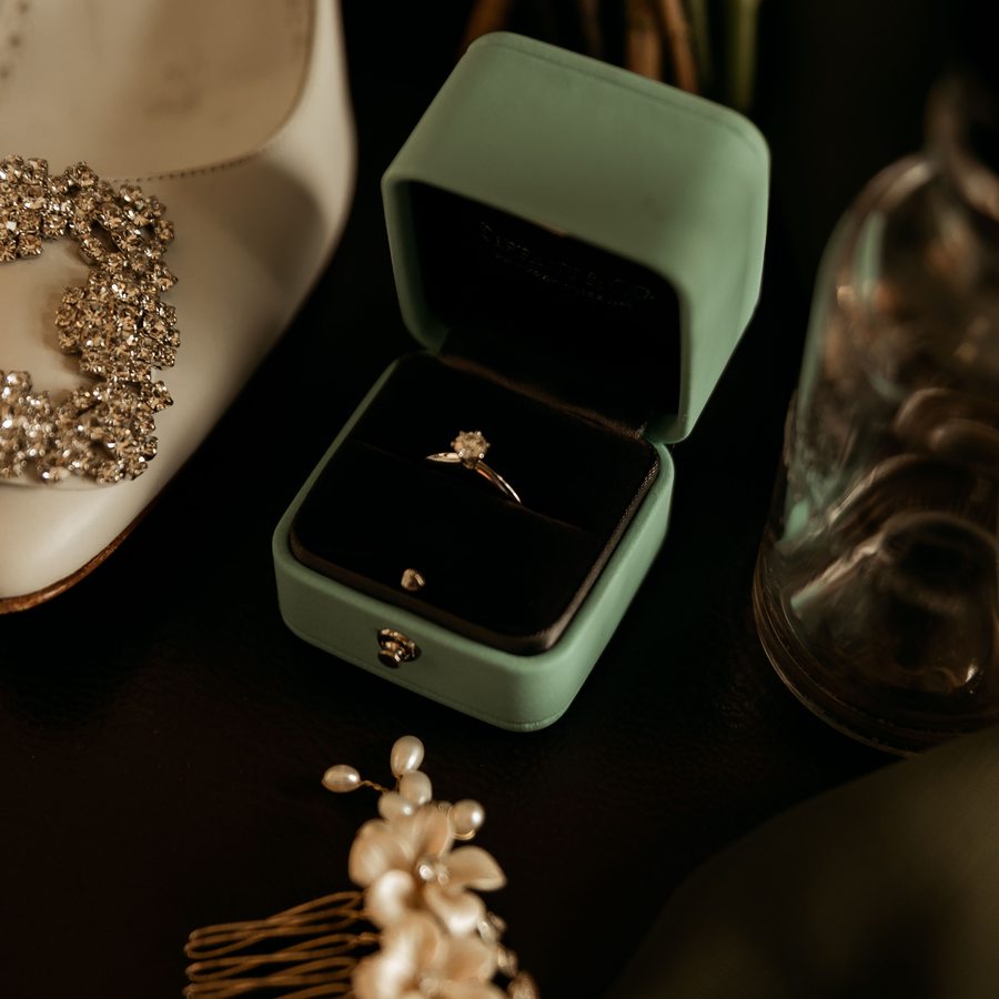 A platinum solitaire engagement ring photographed close-up on a dark stone surface